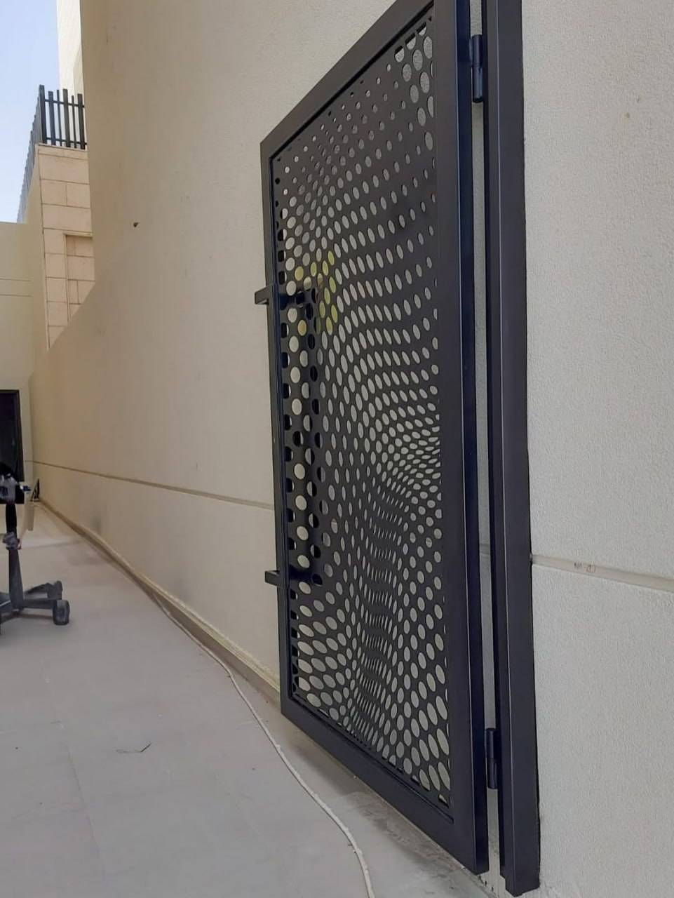 Contemporary bespoke perforated metal gate on a walkway