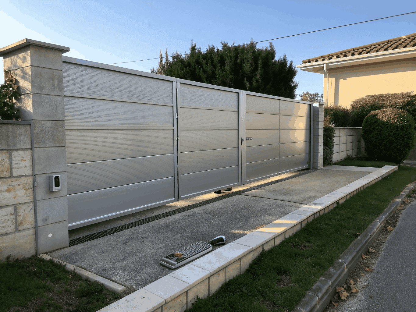 Bespoke double steel slatted driveway gate with staggered-height slats and brick paving