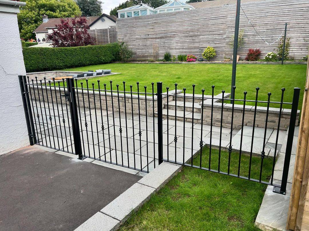 Traditional black spear-top steel railing running alongside garden steps, matching installation