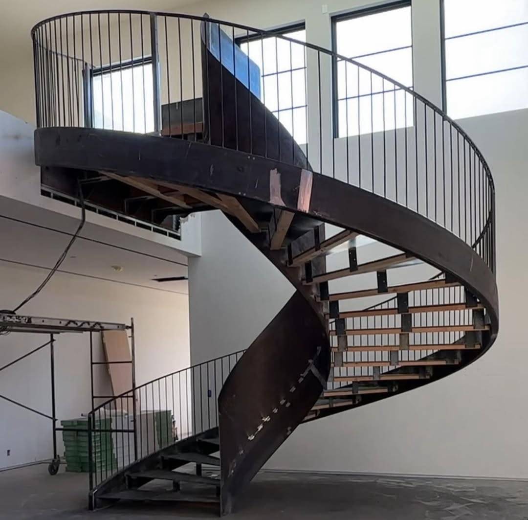 large black steel double-curve helical staircase connecting two levels with vertical bar balustrade