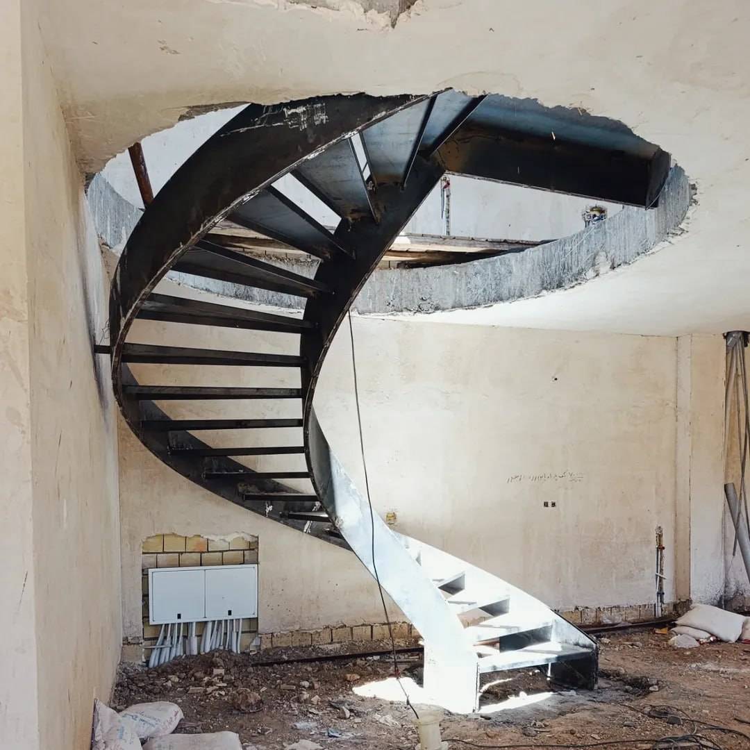 raw primed steel helical staircase mid-fabrication, open centre visible