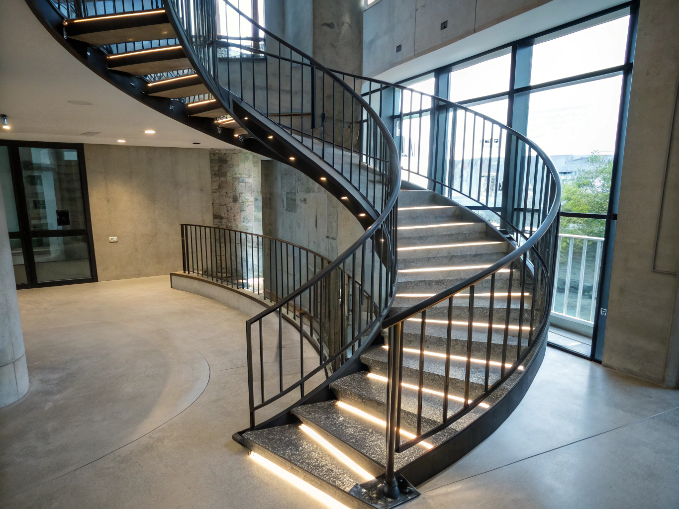 Brushed steel spiral staircase with steel treads in sun-drenched minimalist interior